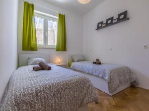 two beds in a bedroom with green curtains at Apartment Color Green in Dramalj