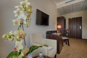 a hotel room with a desk and a flower at Hotel Trzebnica in Trzebnica