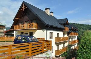 a house with a blue car parked in front of it at Hotel Orlik in Krynica Zdrój