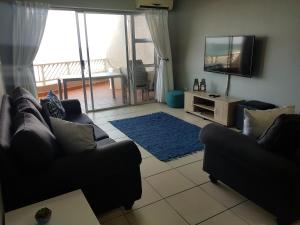 ein Wohnzimmer mit zwei Sofas und einem Flachbildfernseher in der Unterkunft 17 Isikhulu in Umdloti