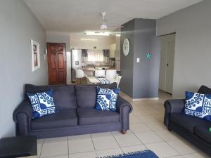 ein Wohnzimmer mit einer blauen Couch und einer Küche in der Unterkunft 17 Isikhulu in Umdloti