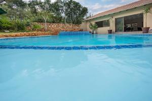 uma grande piscina com água azul em frente a uma casa em Three Oaks and an Aloe Boutique Hotel em Hartbeespoort