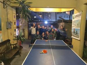 a group of people standing around a ping pong table at Backpacker's Hostel Iquique in Iquique