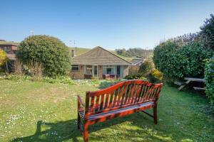 a bench sitting in the grass in front of a house at Dean Court Bungalow - Parking - by Brighton Holiday Lets in Rottingdean