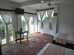 a bedroom with a bed, chair, table and window at Hotel Tiktaalik in Puerto Escondido