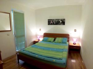 a bedroom with a bed and two lamps on two tables at Green Apartman in Rafailovici