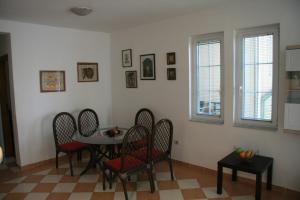 a dining room with a table and chairs and windows at Green Apartman in Rafailovici