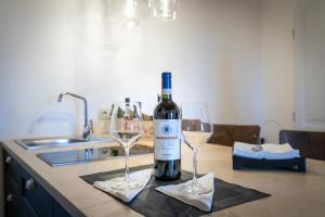 una bottiglia di vino e due bicchieri di vino su un bancone della cucina di Caratello smart studio Apt a Montepulciano