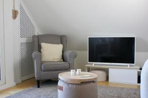 ein Wohnzimmer mit einem Stuhl und einem TV in der Unterkunft SchoenHier-Timmendorf in Timmendorfer Strand