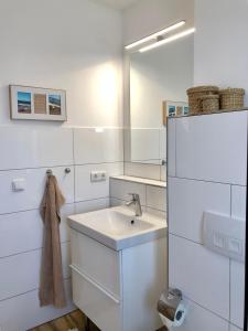 ein weißes Badezimmer mit einem Waschbecken und einem Spiegel in der Unterkunft SchoenHier-Timmendorf in Timmendorfer Strand