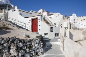 a red door on a white building with a wall at Sweet nectar villa at Pyrgos with heated jacuzzi in Pyrgos