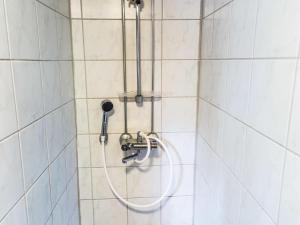 a shower with a hose in a white tiled bathroom at Holiday Home Tievatupa 2- pienempi by Interhome in Ylläsjärvi