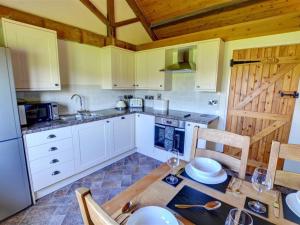 a kitchen with white cabinets and a table with chairs at Holiday Home Corlan by Interhome in Llandinam
