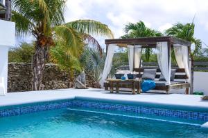 a pool with a gazebo next to a swimming pool at Villa Hakuna Matata Bonaire - Pool & Sea View in Kralendijk