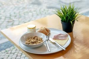 a plate with a bowl of cereal and bread on a table at Stay Hotel Faro Centro in Faro