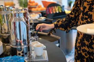 a woman is making a cup of coffee at Stay Hotel Faro Centro in Faro