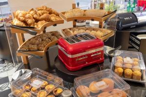 a counter with trays of pastries and trays of bread at Stay Hotel Faro Centro in Faro
