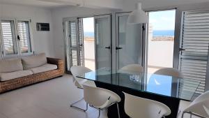 a dining room with a glass table and white chairs at Casa La Vista - Bungalow with fantastic sea views in Arguineguín