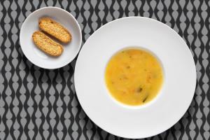 a plate with a bowl of soup and two pieces of bread at Stay Hotel Faro Centro in Faro