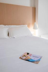 a white bed with a book on it at Stay Hotel Faro Centro in Faro