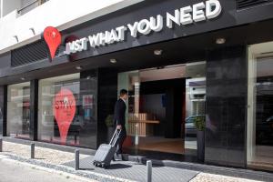 un homme marchant devant un magasin avec une valise dans l'établissement Stay Hotel Faro Centro, à Faro