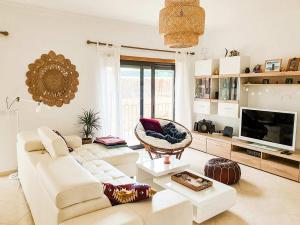 a living room with a white couch and a television at Casa Mawi in Sagres