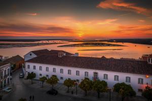 a sunset over a white building in front of a body of water at Stay Hotel Faro Centro in Faro