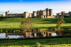 a castle on a hill with a pond in front at Percy Terrace Bed and Breakfast in Alnwick
