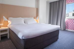 a large bed in a hotel room with a window at Stay Hotel Faro Centro in Faro