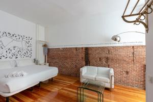 een slaapkamer met een wit bed en een bakstenen muur bij Apartamentos Matute 11 in Madrid