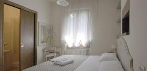 a white bedroom with a bed and a window at La Spiga in Campi Bisenzio