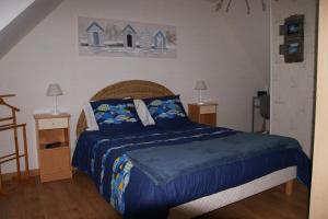 a bedroom with a bed with a blue comforter at La Kerandière in Tonquédec