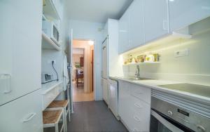 una cocina con armarios blancos y fregadero en Apartamento con vistas al mar, en Santiago de la Ribera