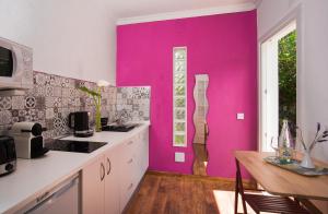 une cuisine avec un mur rose et une table dans l'établissement Estudio rural - Nature & Relax, à La Orotava