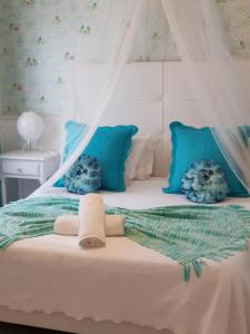 a white bed with blue pillows and a canopy at Casa da Alagoinha in Vila Nova de Milfontes