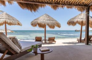 a beach area with chairs, tables and umbrellas at El Pez a Colibri Boutique Hotel in Tulum