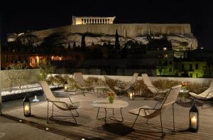 a group of chairs and a table on a patio at night at Herodion Hotel in Athens