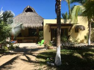 een huis met een rieten dak en een palmboom bij Un Escondite Mágico in Barra de Potosi