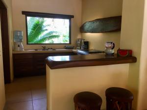 uma cozinha com um balcão com dois bancos e uma janela em Un Escondite Mágico em Barra de Potosi
