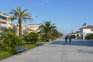 a couple of people walking down a sidewalk with palm trees at VILLETTA CON GIARDINO in Lido di Camaiore