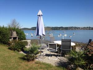 a table and chairs with an umbrella and boats in the water at St Guenole' Studio Apartment in Landévennec