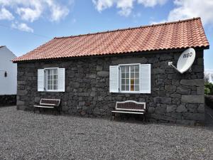 a stone building with two benches in front of it at Casa Caminho da Barca in Madalena