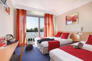 a hotel room with two beds and a balcony at The Originals City, Hôtel Villancourt, Grenoble Sud in Le Pont-de-Claix