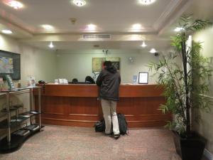 a man standing at a counter in a waiting room at Cassandra Hotel in Vancouver