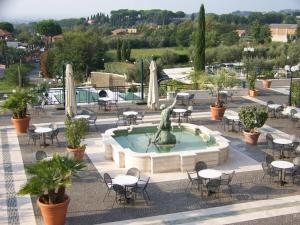 una fuente con una estatua en un patio con mesas y sillas en LH Hotel Domus Caesari, en Marino