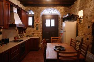 a kitchen with a wooden table and a refrigerator at Traditional Tower in the center of kalamoti in Chios