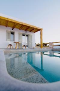 a swimming pool with two chairs next to a house at Aeris suites in Koufonisia