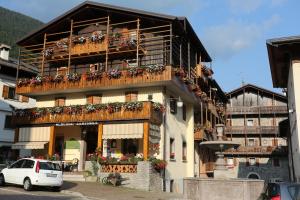 a building with a balcony with flowers on it at Albergo Centrale in Forni di Sopra