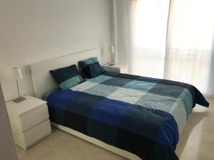 sypialnia z łóżkiem z niebieską kołdrą i oknem w obiekcie Marbella - Estepona beach frontline apartment w mieście Estepona +28 zdjęć