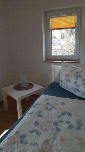 a bedroom with a bed and a table and a window at Ferienhaus Schrammsteinblick in Altendorf